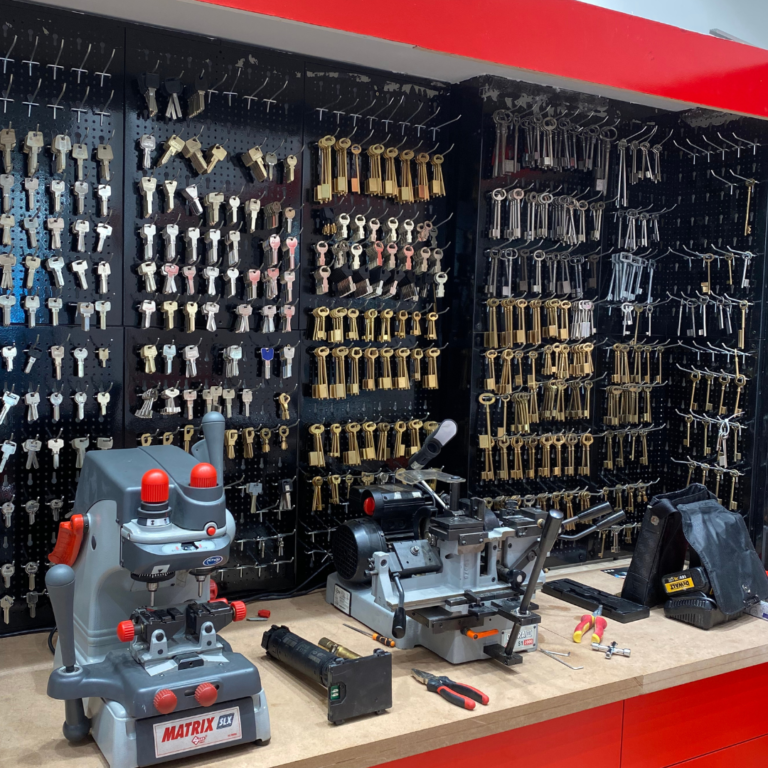 Atelier en magasin : machines de reproduction de clés et présentoir de modèles chez O.M.S Sécurité.